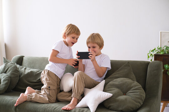 kids boys twins using smartphones on the couch in living room