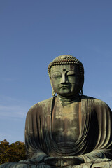 Great Buddha of Kamakura against a clear blue sky, capturing the serene expression of the iconic Daibutsu statue

