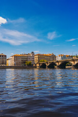 Naklejka premium Palacky Bridge. Boats cruising under historic stone bridge with buildings.
