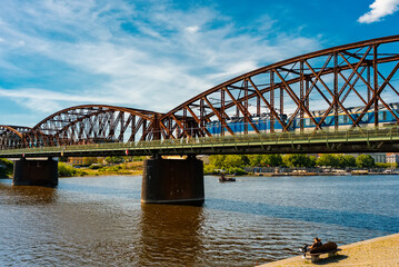 Train crossing large metal arch railway bridge over river.