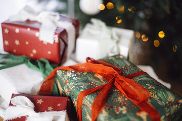 Stylish Christmas presents. Merry Christmas and Happy Holidays! Wrapped Christmas gift boxes against xmas tree with lights bokeh. Holiday banner, atmospheric winter time