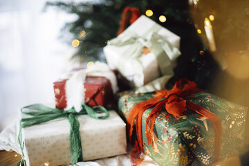 Stylish Christmas presents. Merry Christmas and Happy Holidays! Wrapped Christmas gift boxes against xmas tree with lights bokeh. Holiday banner, atmospheric winter time
