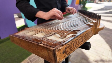 man playing qanun, traditional turkish instrument, kanun, turkish man performing wooden string instrument in Al Ain Zoo Celebration of Independence Day of the UAE.2 December 2025 