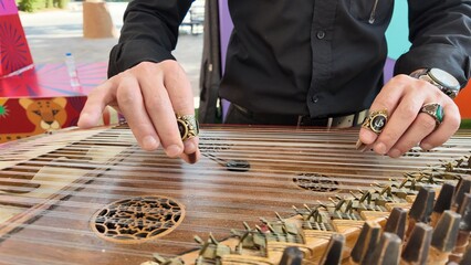 man playing qanun, traditional turkish instrument, kanun, turkish man performing wooden string instrument in Al Ain Zoo Celebration of Independence Day of the UAE.2 December 2025 