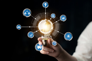 A person holds a glowing light bulb, symbolizing creativity and innovative ideas. Surrounding icons...