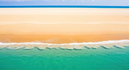 A vast, empty beach with a clear blue sky and calm ocean waves.