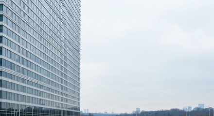 A modern glass skyscraper with a cloudy sky in the background.