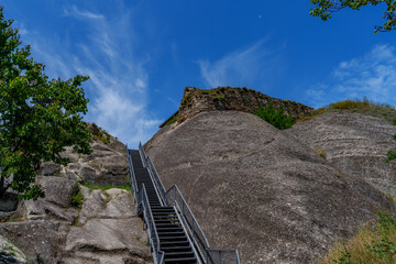 Metal staircase leading up rocky hill under sky