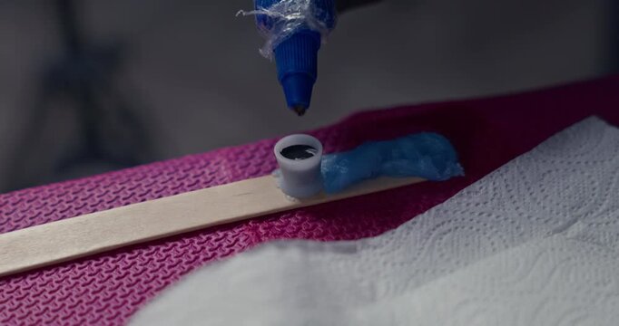 Close-up of pouring black tattoo ink from a bottle into a small ink cap on a workstation with ointment