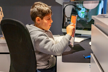 Sad boy using tablet on his bedroom worried due internet and social media risks as cybebyllying and phishing