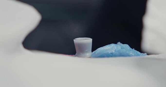 Tattoo artist dipping the needle of the machine into an ink cap filled with black ink before starting work