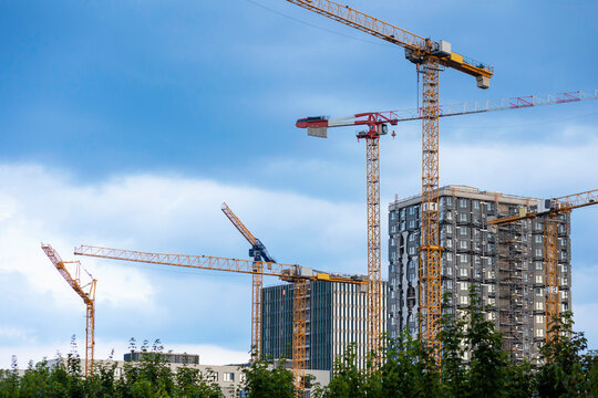 Construction Cranes on Construction Site. Tower Cranes Build Modern High-rise Residential Buildings in Germany City on Sky Background. Copy Space.