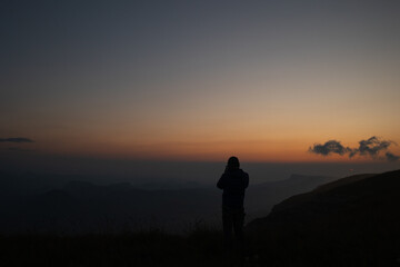 Obraz premium Sunset in the mountains. Silhouette of a man on a dark background of nature while traveling.
