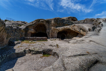 Cave dwellings carved in sandstone at Uplistsikhe under blue sky