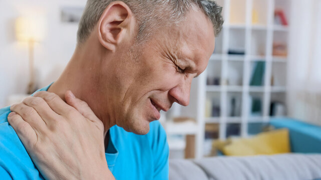 Man touching neck due to pain, possible cervical nerve compression or stress tension