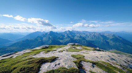 Scenic mountain landscape with a clear blue sky, fluffy clouds, and lush green vegetation. The image captures the beauty of nature on a bright, sunny day.