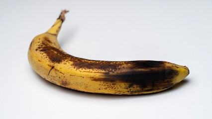 A banana is peeled and has brown spots on it. The banana is sitting on a white surface