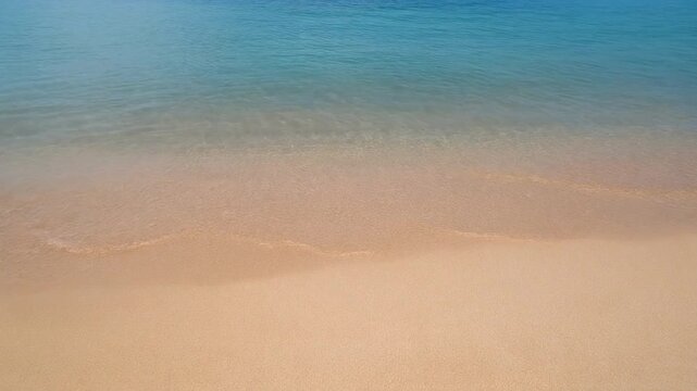 Beach waves gently hitting sand under bright June sun, summer starter mood