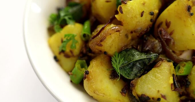 Dry Potato sabzi or Jeera Aloo fry is an Indian lunch/dinner recipe served in a plate with Roti/paratha of Indian bread over colourful/wooden background. Selective focus