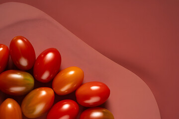 Fresh ripe cherry tomatoes on a textured red surface