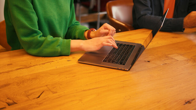 Woman's hands typing on laptop keyboard wooden desk, online technology concept