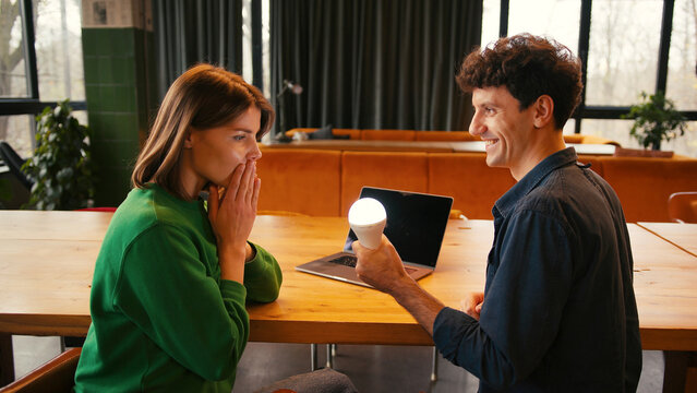 Smiling woman and man brainstorming new idea with light bulb, brainstorming concept - Powered by Adobe