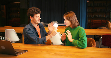 Smiling woman and man brainstorming new idea with light bulb, brainstorming concept