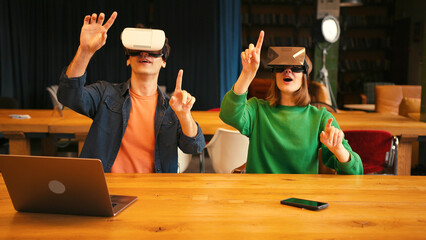 Young couple interacting with augmented reality in vr goggles in modern office