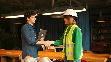 Project manager and female engineer shaking hands in modern office