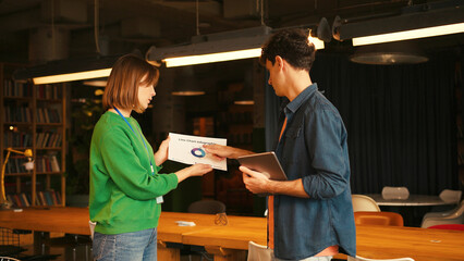 Businesswoman showing project statistics to male colleague in modern coworking