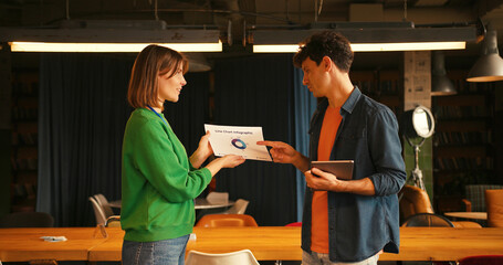 Businesswoman showing project statistics to male colleague in modern coworking