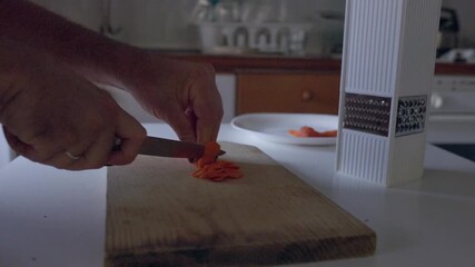 Person slicing fresh carrots on cutting board