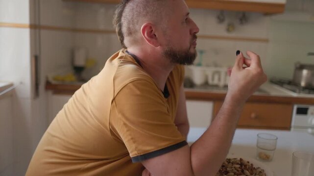 Man with mohawk eating pistachios at home
