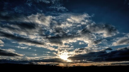 Dramatic sunrise or sunset sky with illuminated clouds creating high contrast between bright whites and dark shadows,