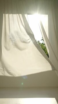 White curtain blowing in wind near open window with sunlight, fresh air and morning breeze home concept, vertical 9:16 background for social media stories