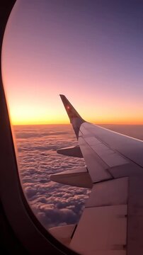 Airplane wing view during sunset flight, orange sky horizon and clouds, air travel journey background, vertical 9:16 background for social media stories