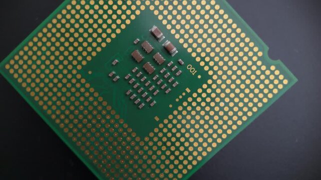 Macro rotating view of a CPU underside with gold contact grid, showing detailed processor elements suitable for hardware and tech-oriented footage