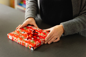 Gift box wrapped with red ribbon and berries. Sustainable or luxury Christmas present on a dark background.