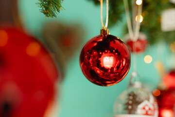 Shiny red Christmas bauble hanging. Foreground holiday decoration with blurred commercial background (bokeh) for holiday promotions.