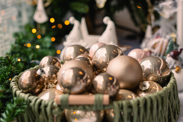 Wicker basket with golden Christmas baubles on a rustic blanket. Homemade holiday decorations for the Christmas tree.
