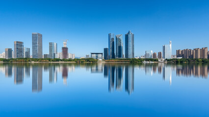 Fototapeta premium Modern city skyline with calm water reflection under clear blue sky