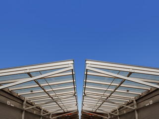 Obraz premium Minimalistic Glass Roof With Metal Support Beams in Modern Architectural Design Under Blue Sky for Construction Engineering Industries, Urban Bazaar Infrastructure, Retail Trade, Dir Designs.