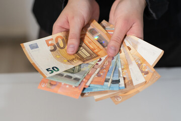 A businesswoman holding several euro banknotes, demonstrating finance, wealth, currency, and business economic growth. Buying, issuing money, borrowing, lending, repaying debt, loan interest