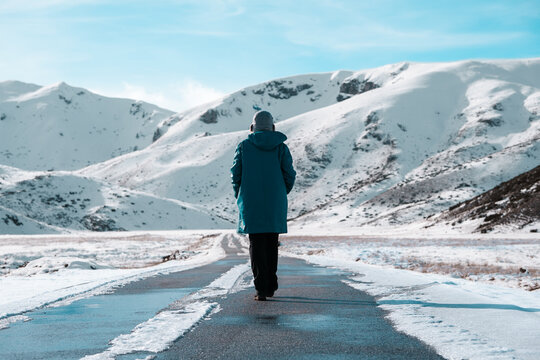 Woman hiking in snow covered mountains, winter clothing walk