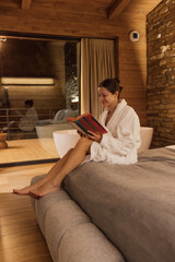 Relaxing woman reads a book in a cozy wooden cabin at night