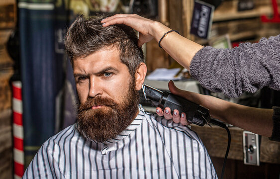 Man visiting hairstylist in barbershop. Barber woman haircut a bearded man in a barber shop - Powered by Adobe