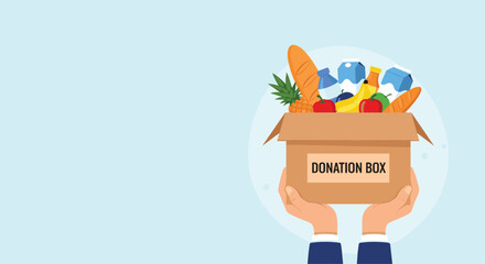 Two hands holding up a cardboard donation box full of fresh food and groceries for a charity drive or humanitarian aid project.