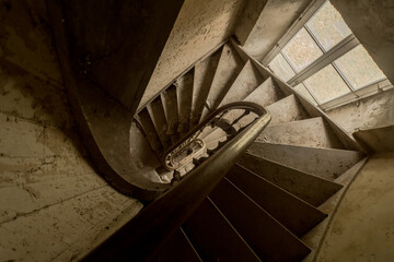 Fototapeta premium Dusty Spiral Staircase Inside an Abandoned Belgian Building - Top-Down View