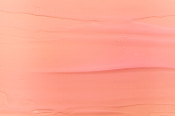 Cosmetic shimmering oil gel balm pink coral peach texture background. Beauty product sample swatch