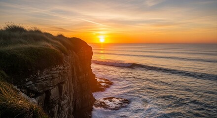 Golden sunset over a rugged coastal cliff with waves crashing below, creating a serene ocean landscape.